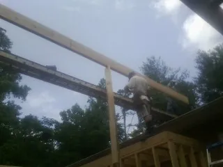 Carpenter setting a ridge beam over a new addition frame — Ice Dam Removal by Roofing Brothers in Luxemburg