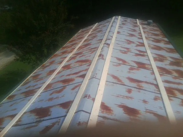 Rusted metal roof panels with new wood purlins before replacement — Storm Damage Roof Repair in Luxemburg by Roofing Brothers