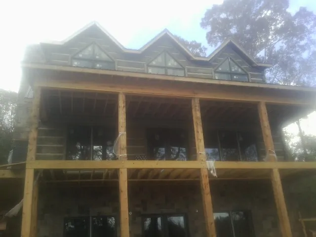 Dormers and porch framing on a large log home under construction — Roof Coating work by our crew in Luxemburg