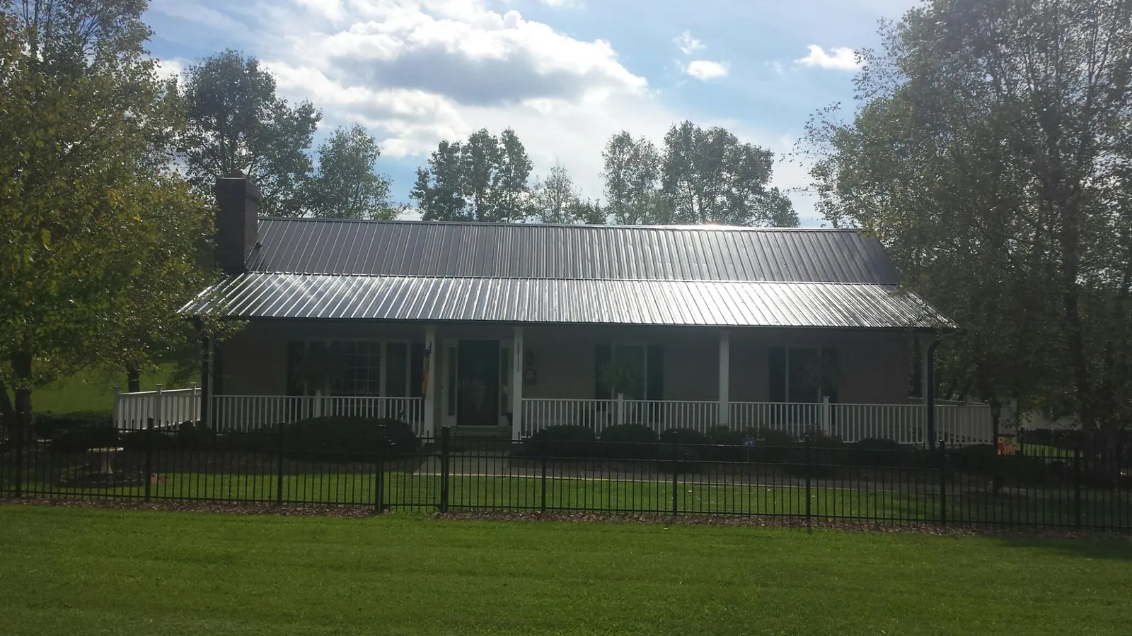 Gray metal roof on a brick ranch with a full width front porch — Gutter Guard Installation work by our crew in Luxemburg