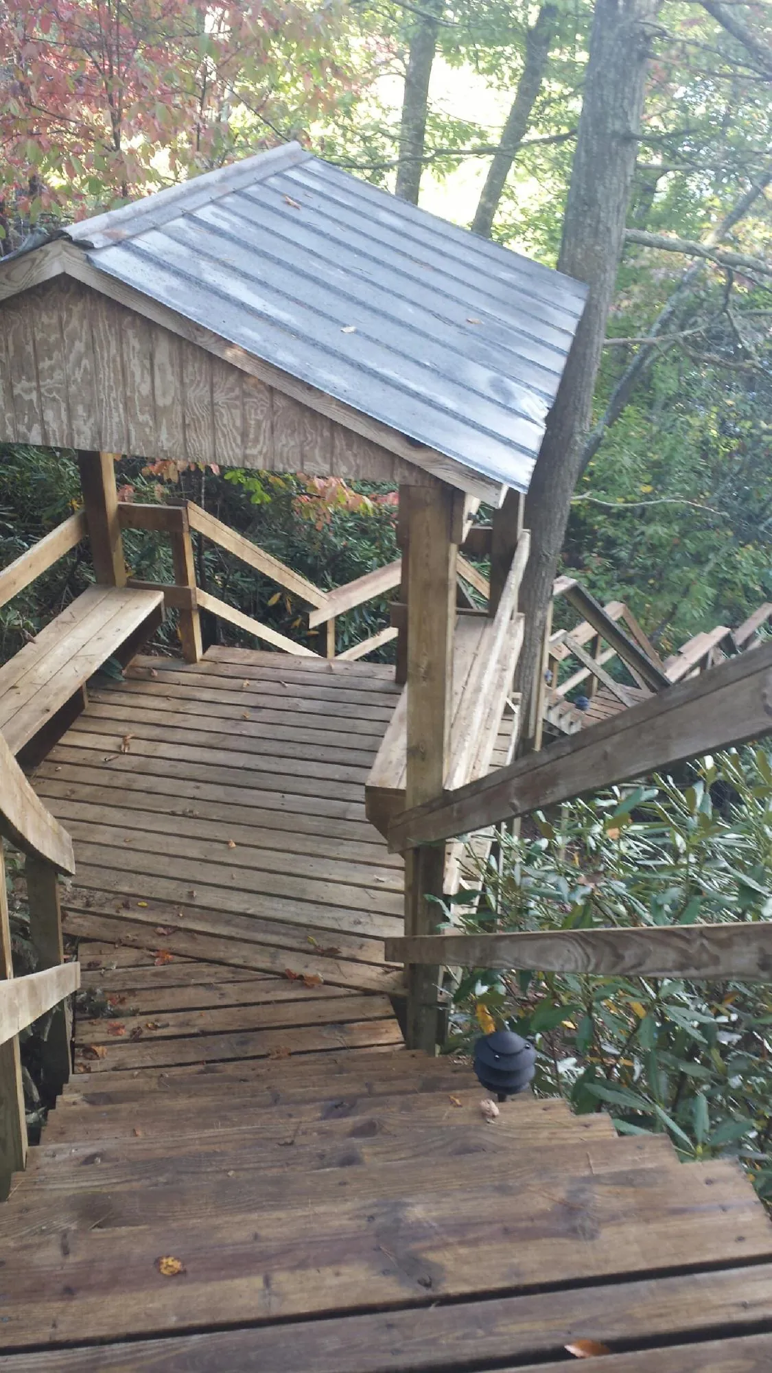 Metal roofed shelter over wooden steps on a wooded walkway — Skylight Repair & Installation work by our crew in Luxemburg