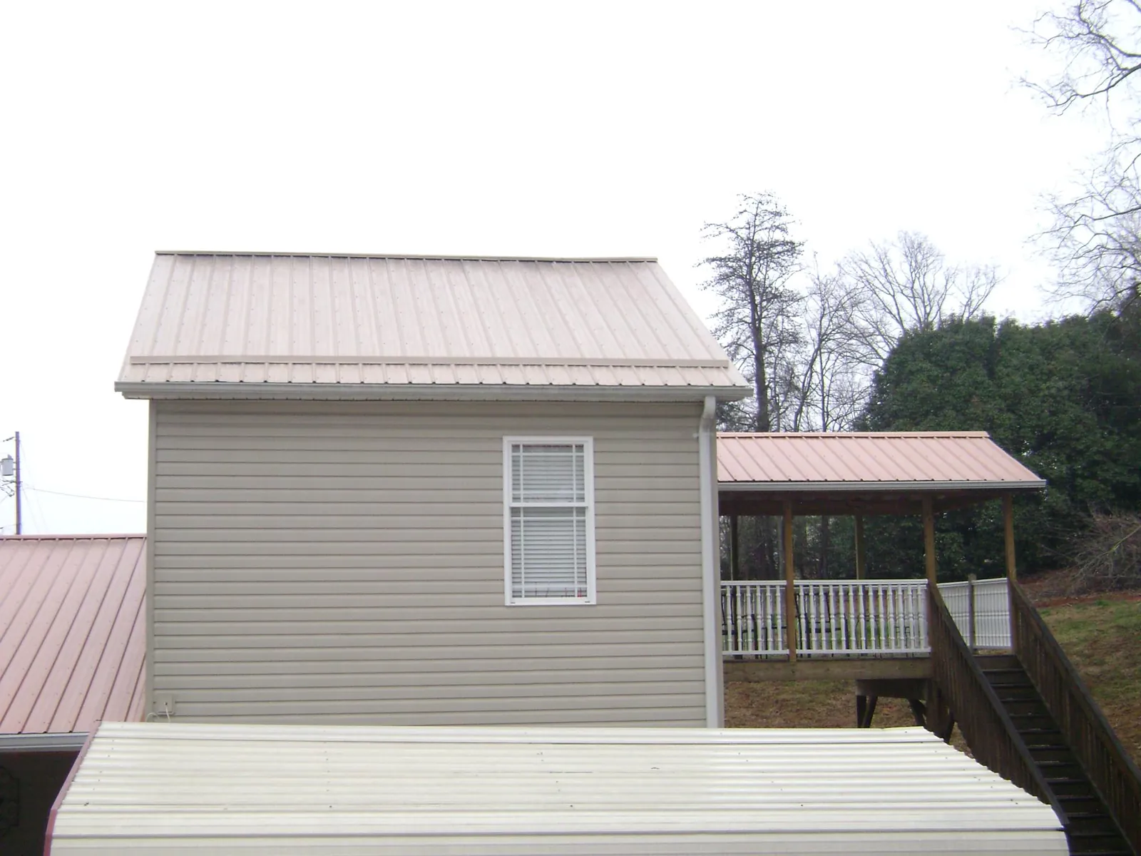Tan metal roofs on a two story addition and attached porch, from a Roof Replacement job in Luxemburg