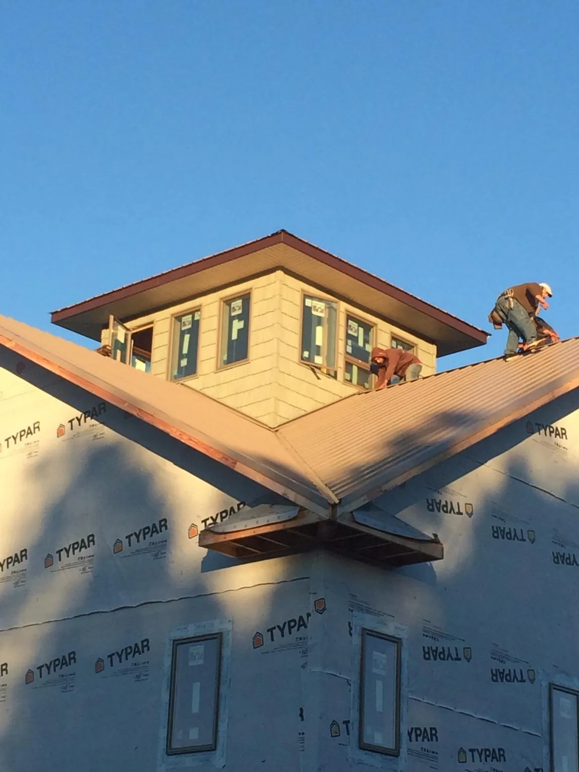 Roofers working around a rooftop cupola on a new metal roof at sunset — Roof Waterproofing in Luxemburg by Roofing Brothers